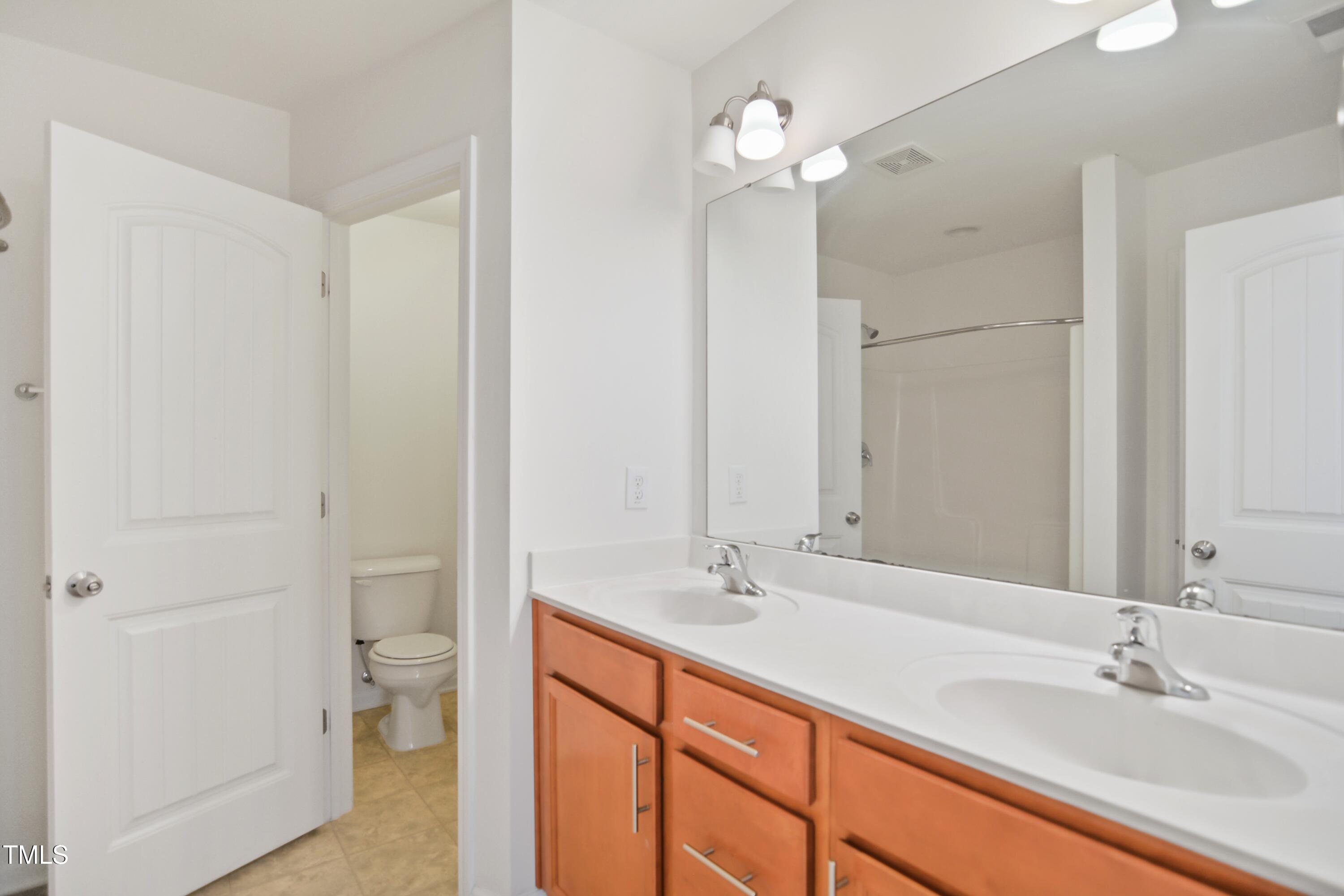 2901 Benevolence Drive Raleigh, NC 27610 - Photo 12 of 18 a bathroom with a double vanity sink mirror and toilet
