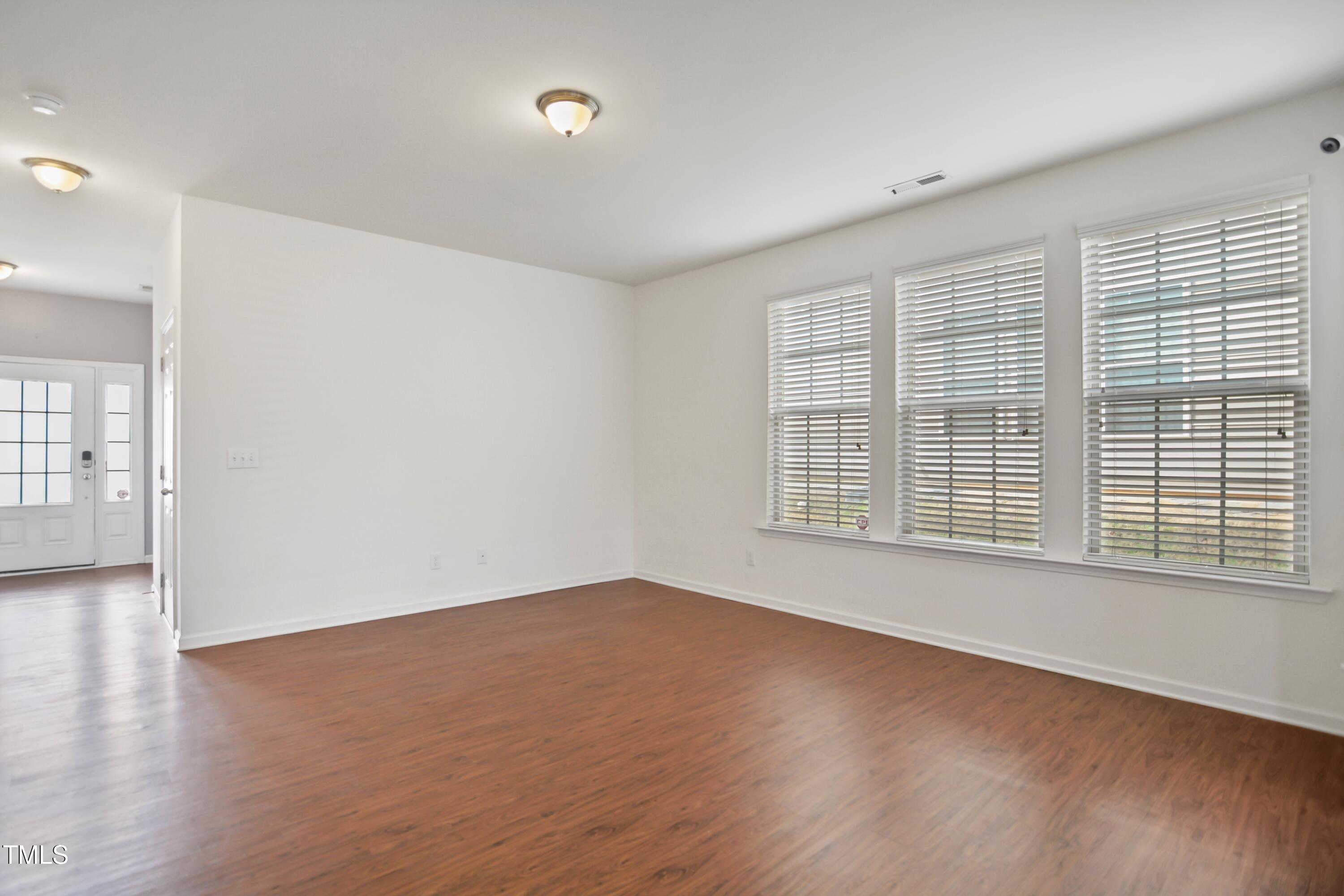 2901 Benevolence Drive Raleigh, NC 27610 - Photo 4 of 18 a view of an empty room with wooden floor and a window