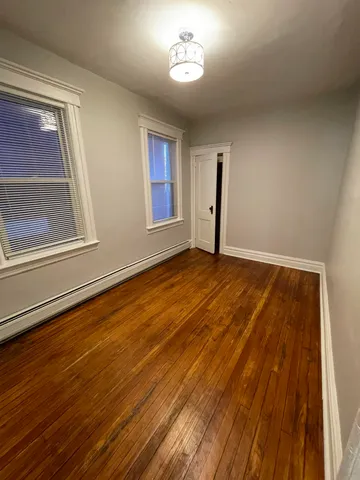 a view of empty room with window and wooden floor