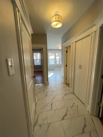 a view of a hallway with wooden floor and chandelier