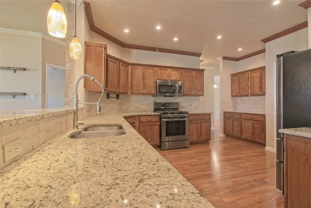 a kitchen with stainless steel appliances granite countertop a stove a sink and a refrigerator