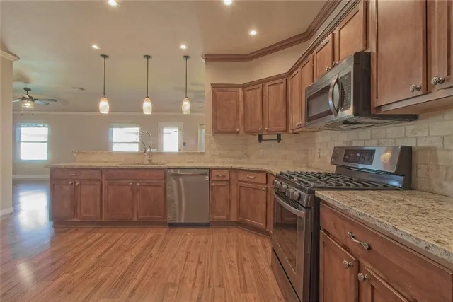 a kitchen with stainless steel appliances granite countertop wooden cabinets stove top oven and sink