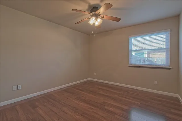a view of a room with wooden floor and a ceiling fan