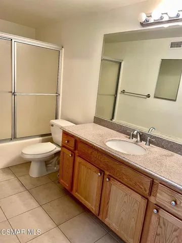 a bathroom with a granite countertop sink a toilet and a mirror