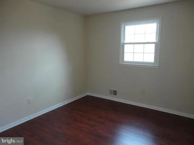 an empty room with wooden floor and window