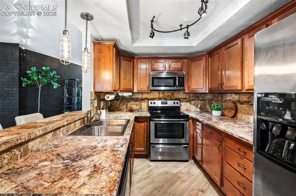 1682 Deer Creek Road Monument, CO 80132 - Photo 13 of 39 Rich wood cabinetry brings warmth, depth, and a sense of timeless craftsmanship. Stainless steel appliances integrate seamlessly for a refined, functional finish, and sculptural lighting elements add subtle drama and architectural interest