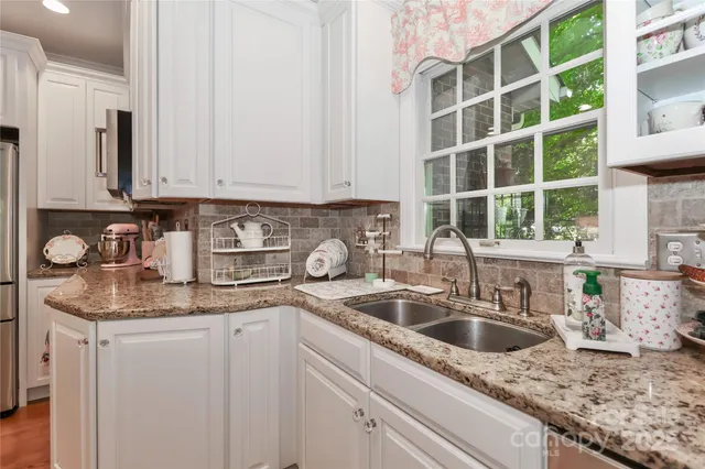 a kitchen with granite countertop a sink a stove and cabinets