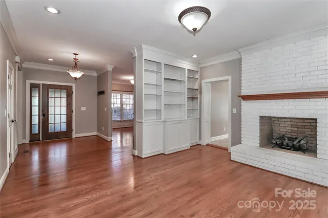 an empty room with wooden floor fireplace and windows