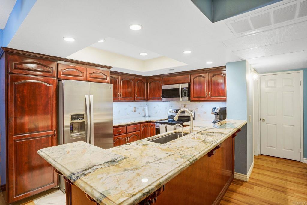 a kitchen with stainless steel appliances granite countertop a sink refrigerator and cabinets