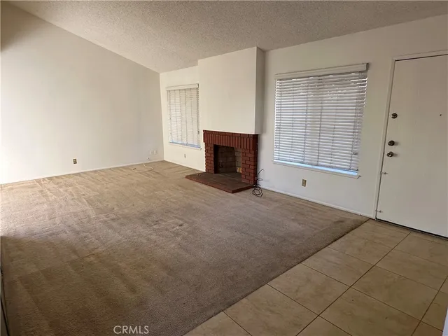 a view of an empty room with a fireplace and a window