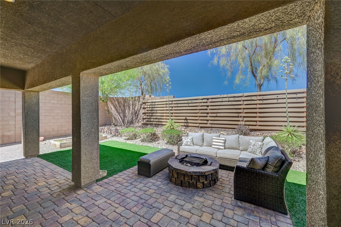 8197 Riley Love Street Las Vegas, NV 89139 - Photo 36 of 48 An inviting covered patio featuring a stone-look fire pit and paved flooring creates an ideal outdoor relaxation space.