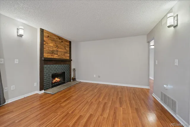 a view of empty room with wooden floor and fireplace
