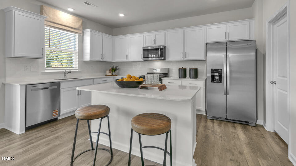 632 Ramo Grande Drive Wake Forest, NC 27587 - Photo 5 of 41 a kitchen with stainless steel appliances granite countertop a table chairs refrigerator and sink