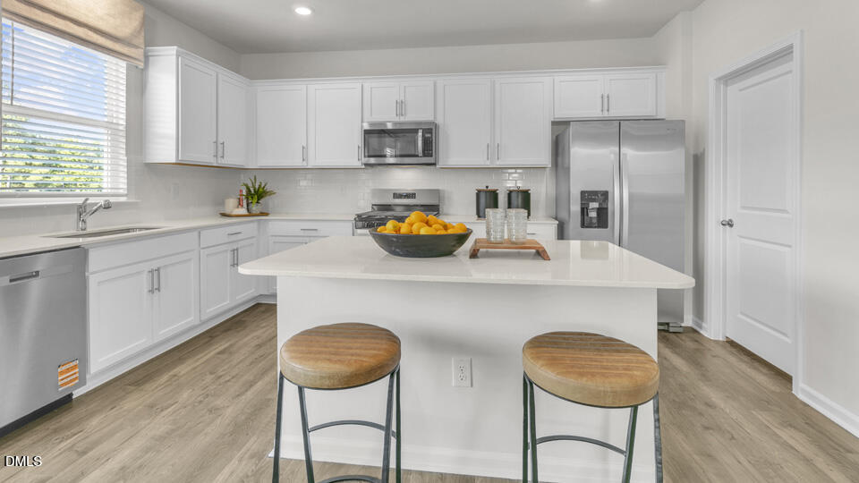 632 Ramo Grande Drive Wake Forest, NC 27587 - Photo 6 of 41 a kitchen with stainless steel appliances a table chairs and wooden floor