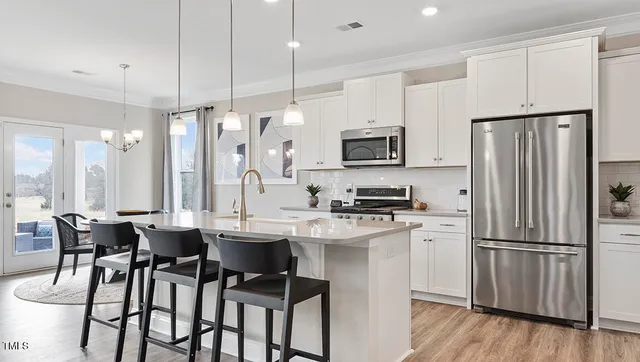 a kitchen with stainless steel appliances a dining table chairs refrigerator and microwave