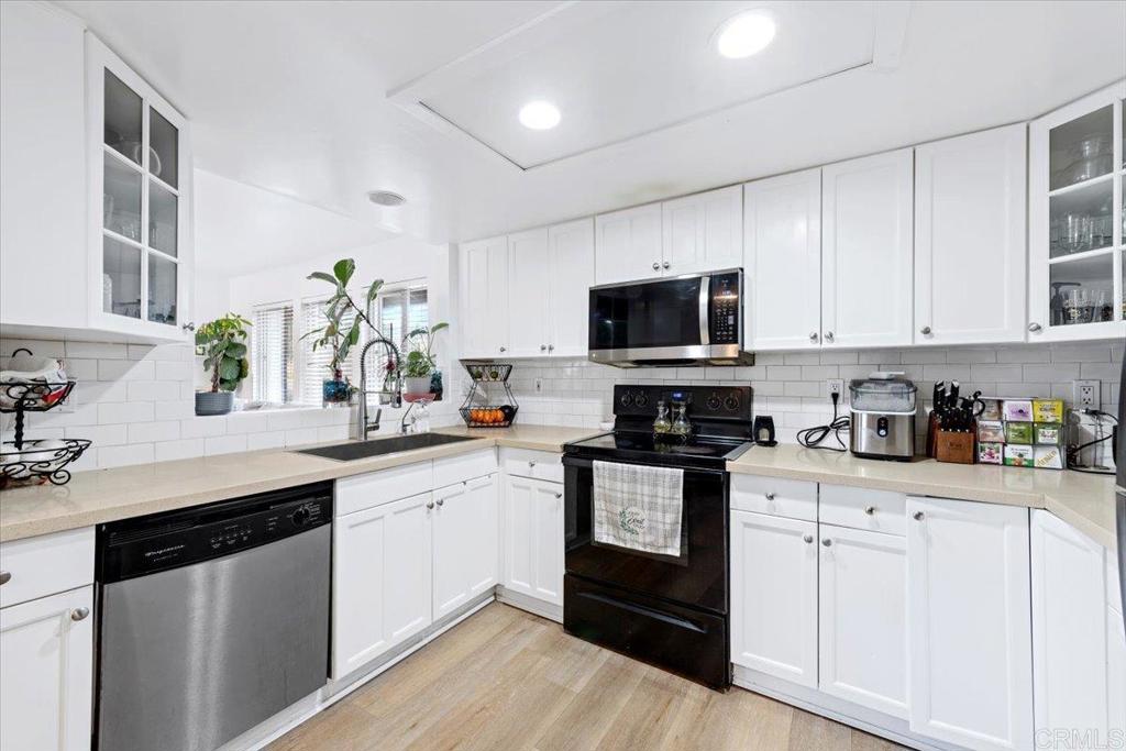 1069 Estes Street El Cajon, CA 92020 - Photo 1 of 35 a kitchen with granite countertop white cabinets sink and stainless steel appliances