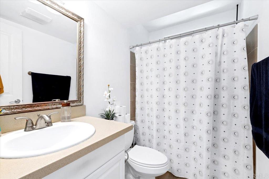 1069 Estes Street El Cajon, CA 92020 - Photo 26 of 35 a bathroom with a sink toilet a mirror and shower curtain
