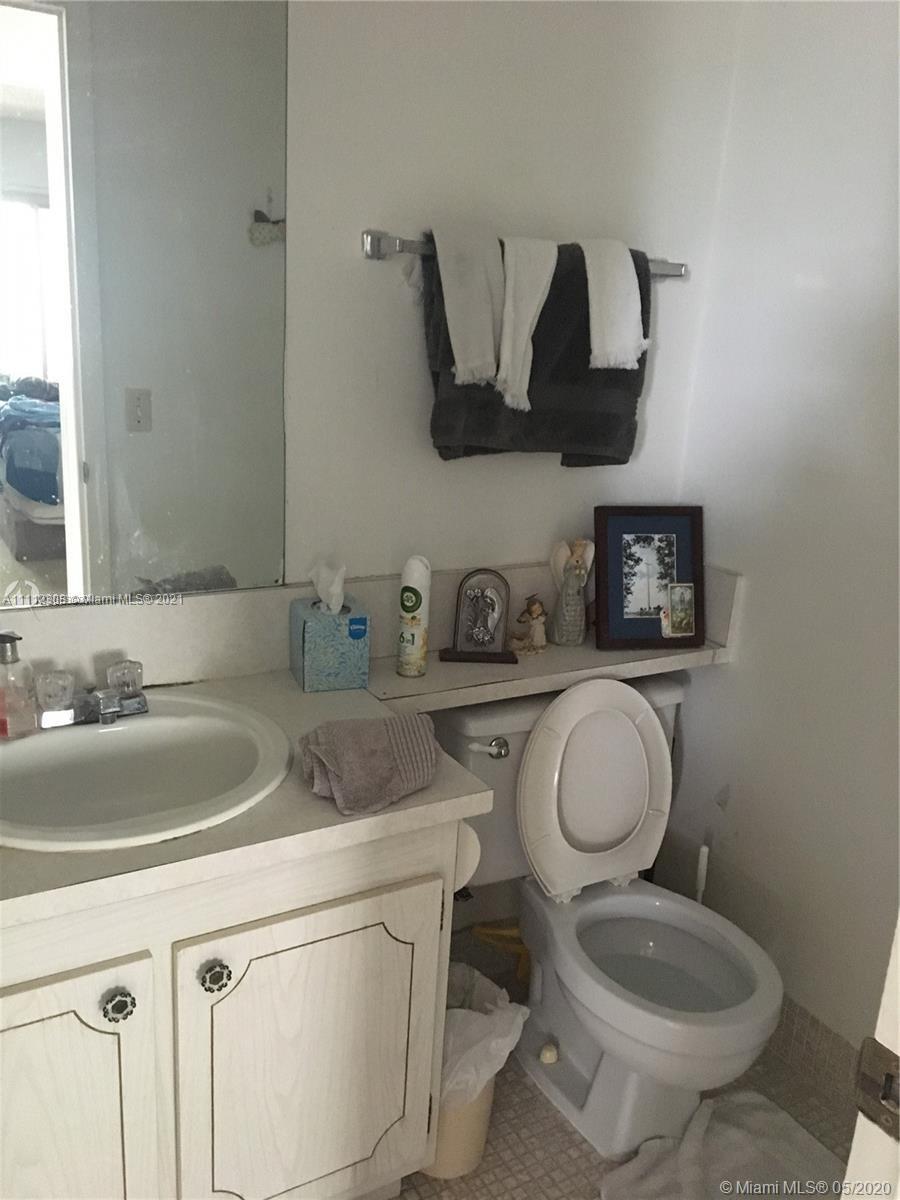 252 Fanshaw F, Unit 252F Boca Raton, FL 33434 - Photo 5 of 8 a white toilet sitting next to a bathroom sink