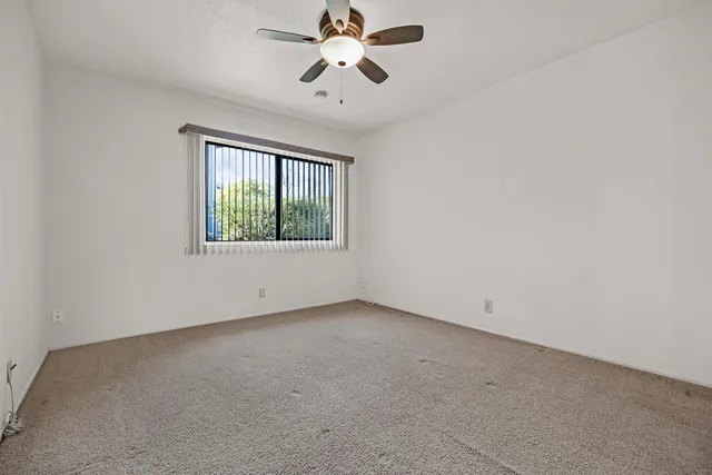 an empty room with a window and a fan