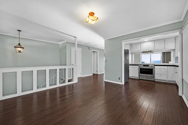 a view of an empty room with a window and wooden floor