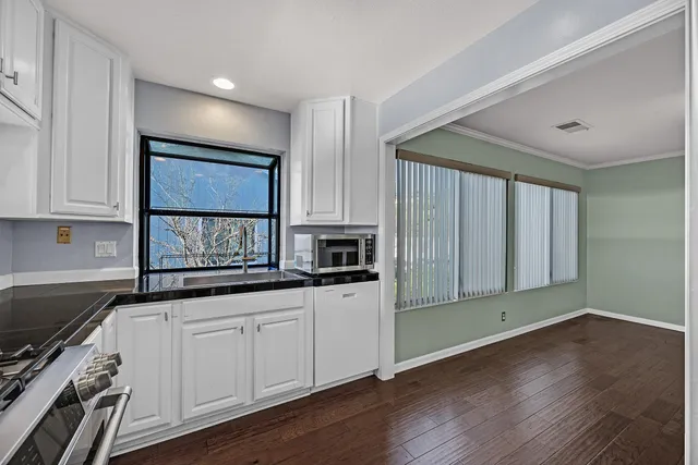 a kitchen with granite countertop white cabinets and wooden floor
