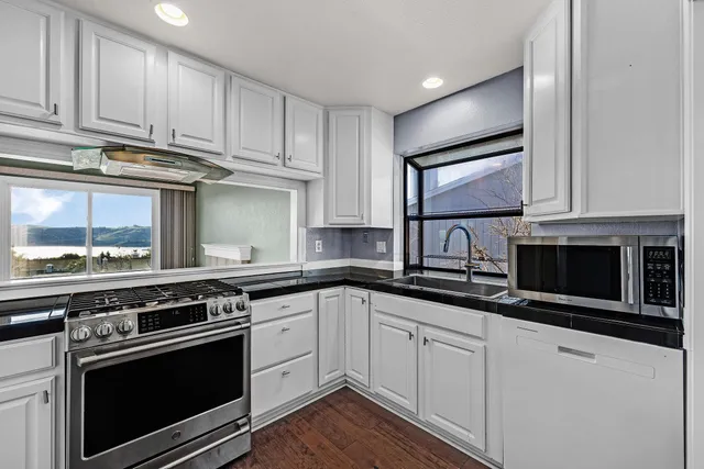 a kitchen with stainless steel appliances granite countertop a stove microwave and cabinets