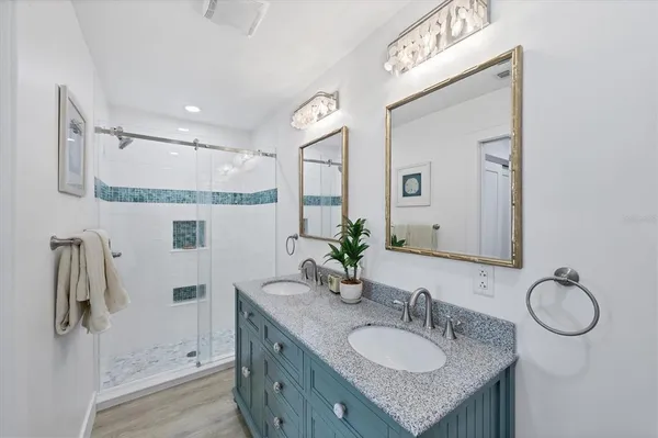 a bathroom with a granite countertop sink a mirror and shower