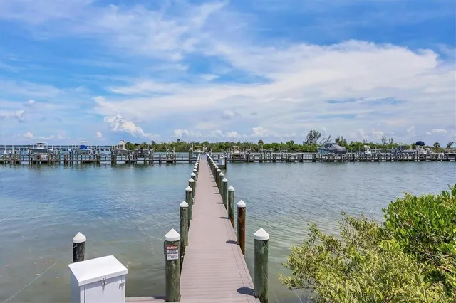 a view of a lake with table and chairs next to a large trees