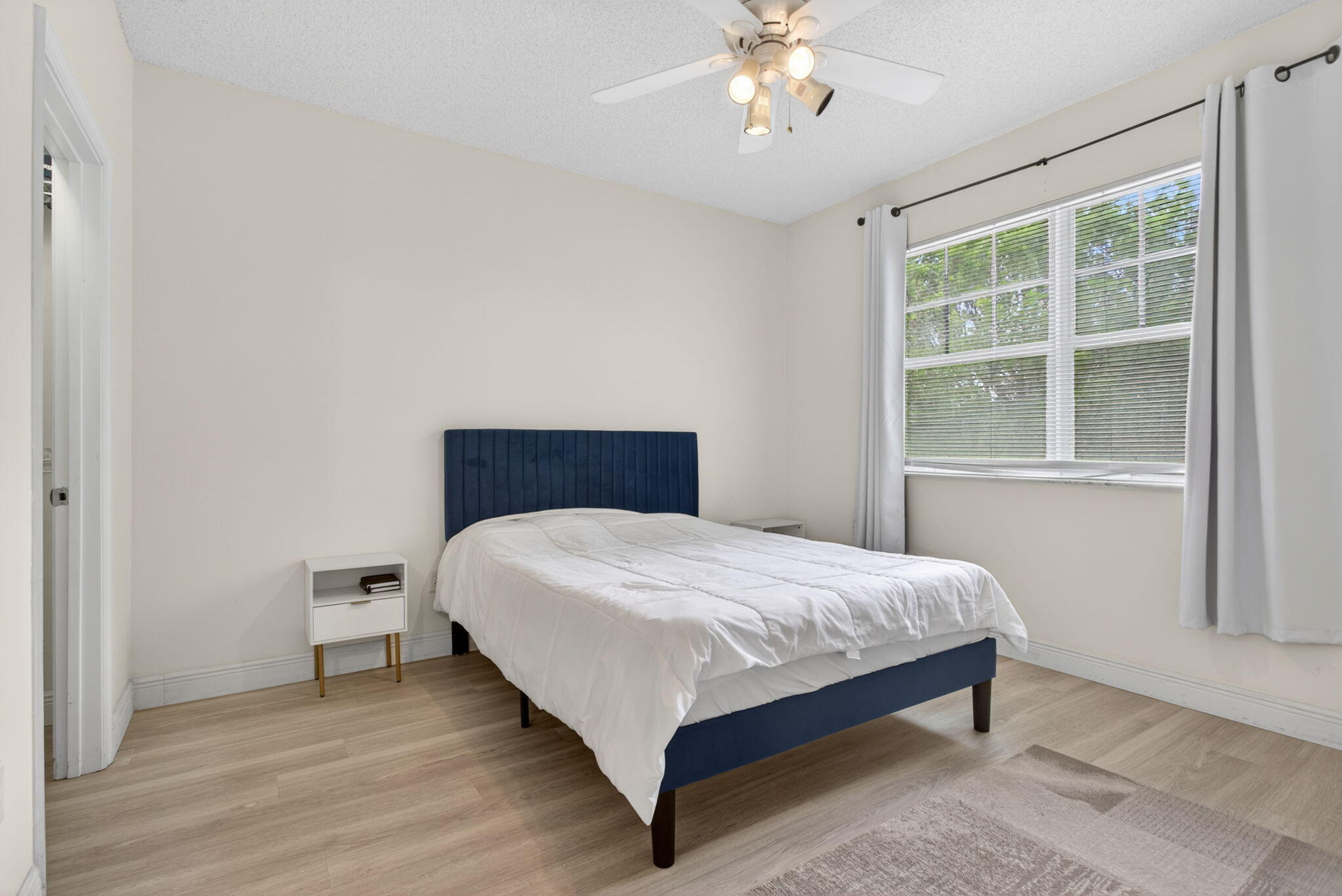 5880 West Sample Road, Unit 206 Coral Springs, FL 33067 - Photo 25 of 37 a large bed sitting in a bedroom next to a window and a chandelier