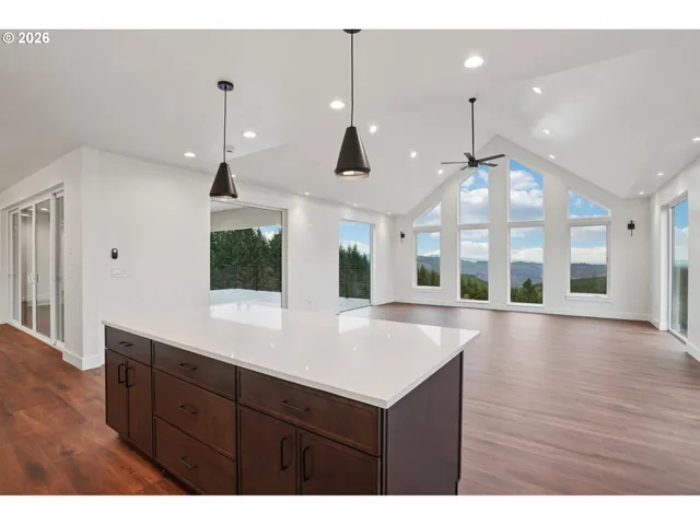 a view of an empty room with wooden floor and a large window