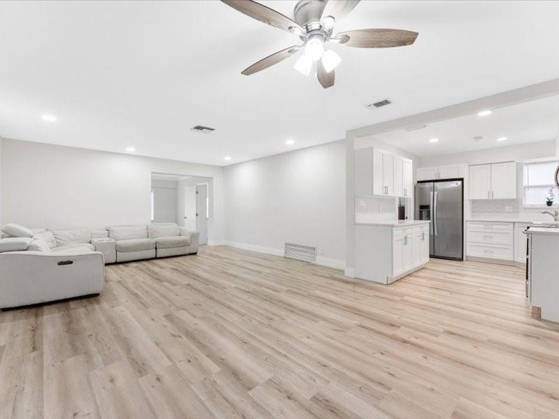 311 West Sample Road Deerfield Beach, FL 33064 - Photo 13 of 34 a view of an empty room and kitchen view with wooden floor