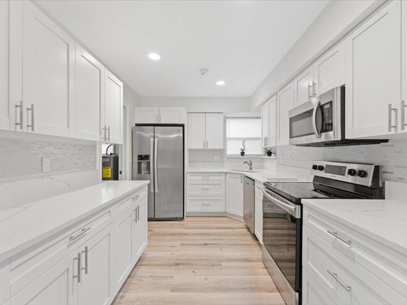 311 West Sample Road Deerfield Beach, FL 33064 - Photo 15 of 34 a kitchen with stainless steel appliances granite countertop a refrigerator and a stove top oven