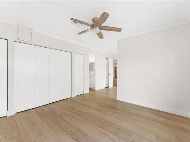 a view of empty room with wooden floor and ceiling fan