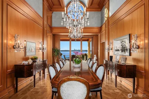 a view of a dining room with furniture a chandelier and large windows