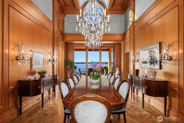 a view of a dining room with furniture a chandelier and large windows