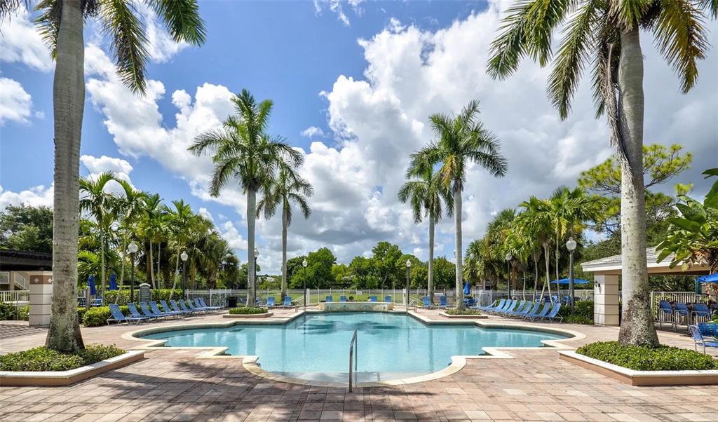 4248 Southeast Cove Lake Circle, Unit 3B06207 Stuart, FL 34997 - Photo 2 of 18 a view of a swimming pool with a lawn chairs and palm trees
