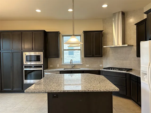 a kitchen with kitchen island granite countertop stainless steel appliances a sink and a refrigerator