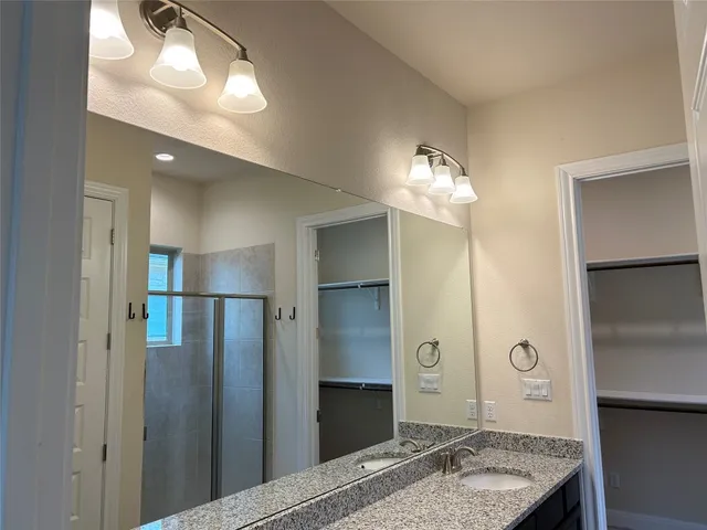 a spacious bathroom with a granite countertop sink a shower and a mirror