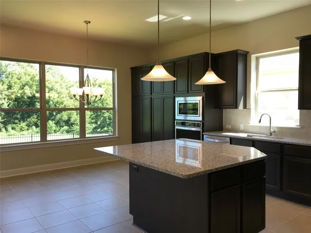a kitchen with kitchen island granite countertop a sink a counter top space and cabinets