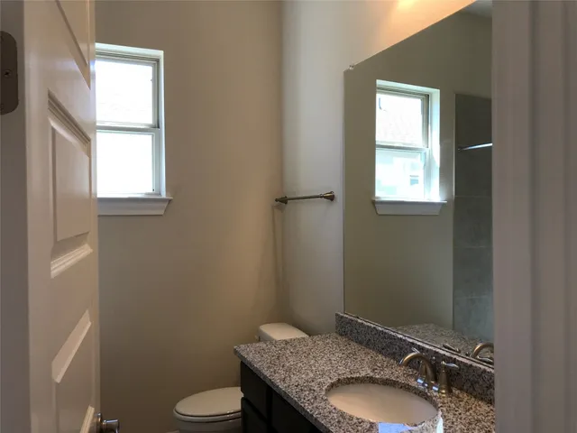 a bathroom with a granite countertop toilet a sink and mirror