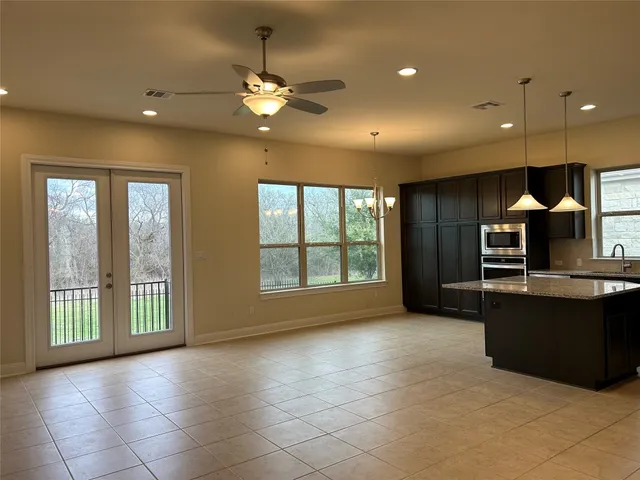 a view of an empty room with kitchen and a window