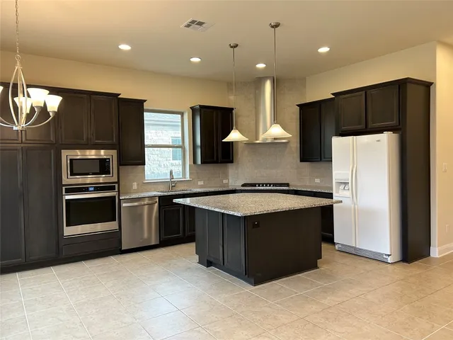 a kitchen with stainless steel appliances granite countertop a refrigerator a sink a stove a microwave and island