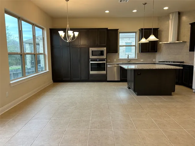 a large kitchen with a large counter top stainless steel appliances and cabinets