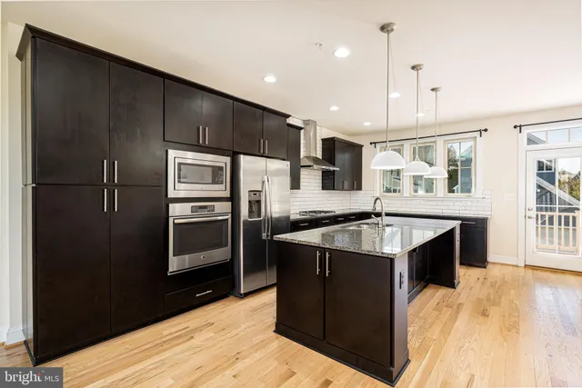 a kitchen with stainless steel appliances kitchen island granite countertop a stove microwave and refrigerator