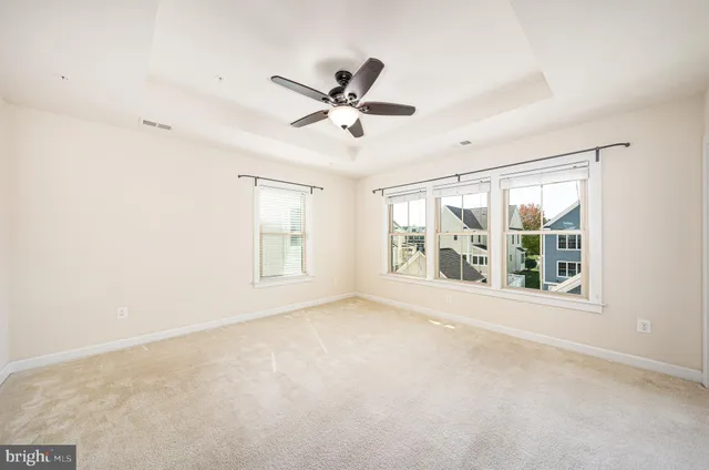 an empty room with windows and ceiling fan