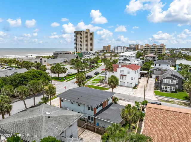 an aerial view of residential houses with outdoor space and ocean view