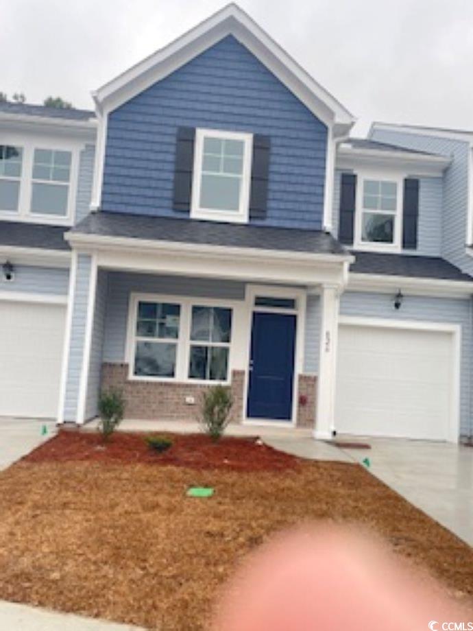 View of front of home with brick siding, concrete driveway, a porch, and a garage