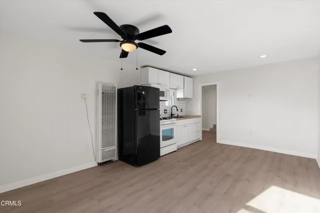 an empty room with chandelier fan and windows