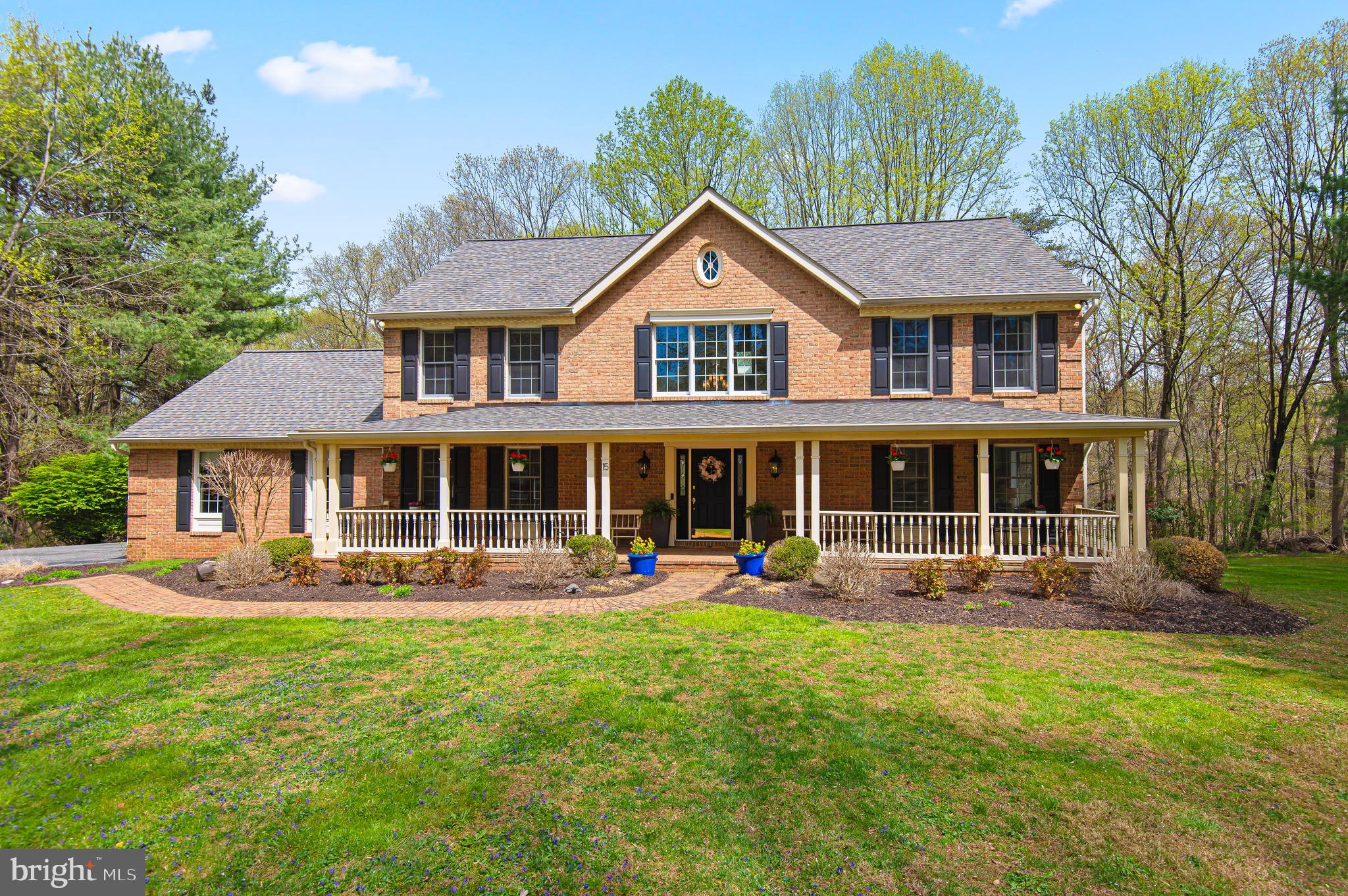 a front view of a house with garden and trees