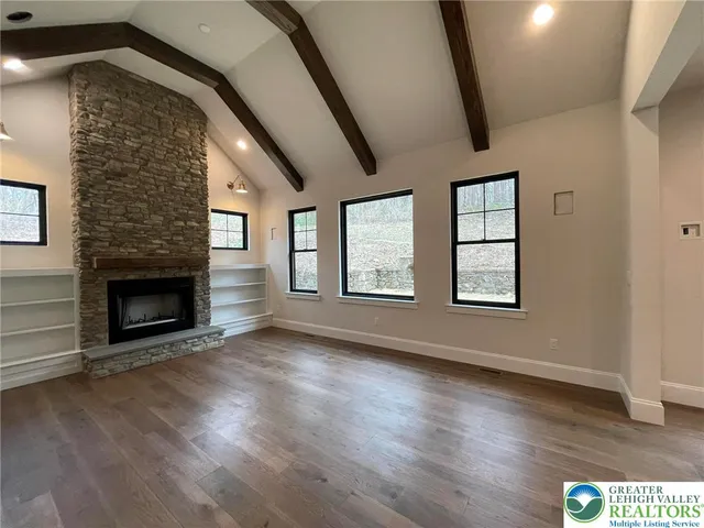an empty room with wooden floor fireplace and windows